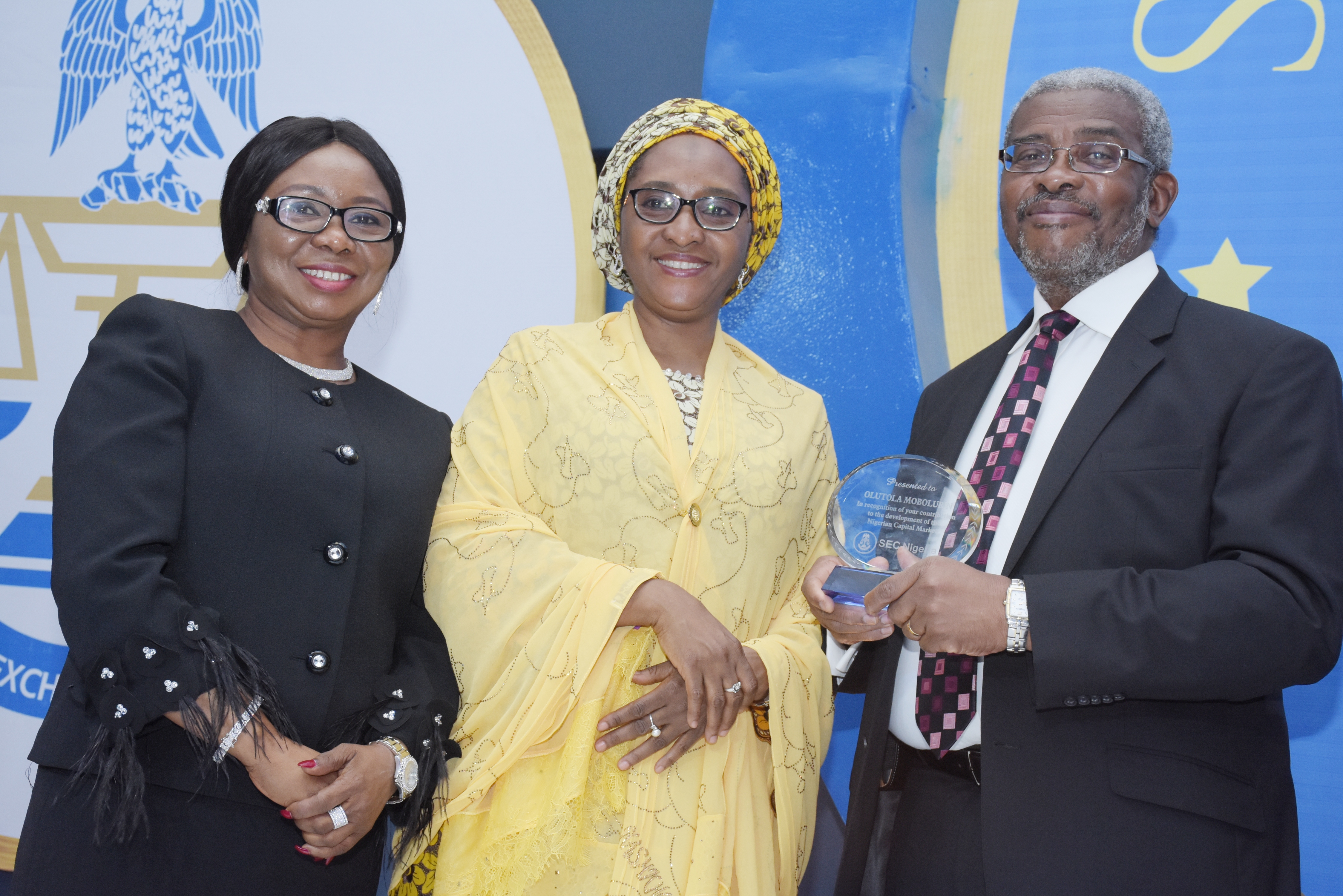 Chairman, Capital Market Masterplan Implementation Council, (CAMMIC), Mr Olutola Mobolurin receives an award plaque from the Minister of Finance, Mrs Zainab Ahmed, supported by the Ag. Director-General, Securities and Exchange Commission, Ms Mary Uduk, (left) at the SEC Awards Night in Lagos on Tuesday, March 19, 2019.