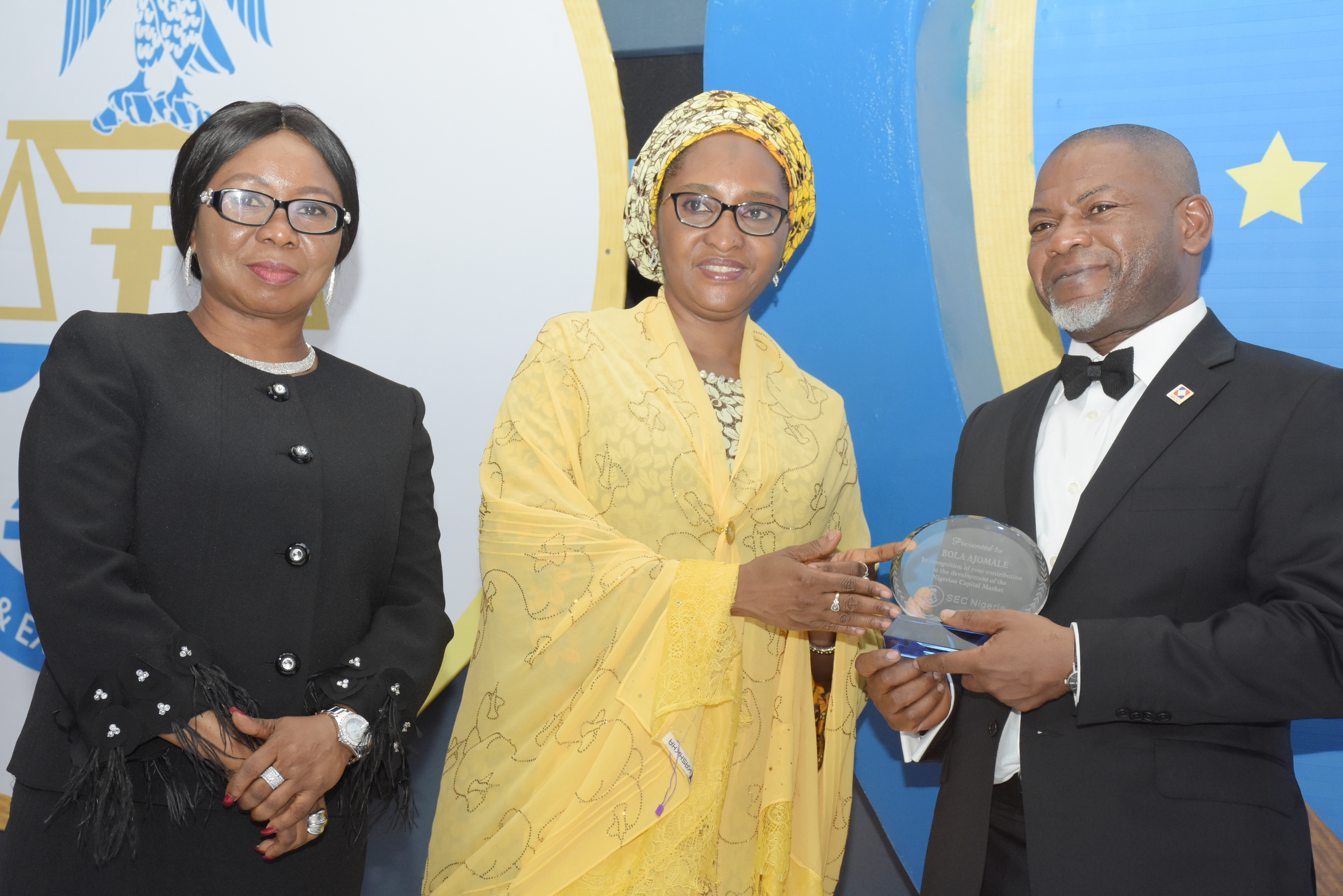L-R:  Ag. Director-General, Securities and Exchange Commission and the Ms Mary Uduk, Minister of Finance, Mrs Zainab Ahmed present an award plaque to Chairman New Listing committee, Mr Bola Ajomale
